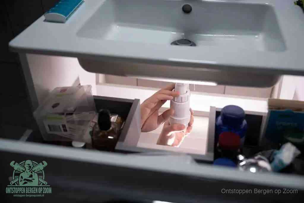 Een pompfles met zeep boven een wastafel, de heet water en afwasmiddel-methode om een vetprop in de afvoer los te maken in Bergen op Zoom
