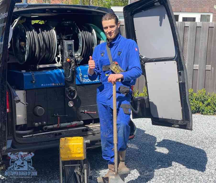 Een monteur bij de werkbus met grote hogedruk-slanghaspels, apparatuur voor hardnekkige afvoerverstoppingen in Bergen op Zoom