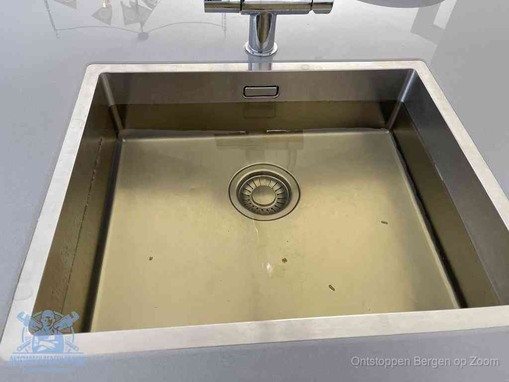 Stilstaand water in een rvs spoelbak dat niet wegloopt, een duidelijk signaal van een gootsteenverstopping in Bergen op Zoom