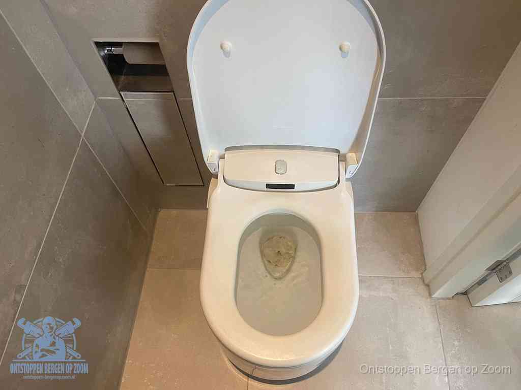 Een wit hangtoilet waarin een prop wc-papier op het water blijft drijven, een duidelijk signaal van een verstopte wc in Bergen op Zoom