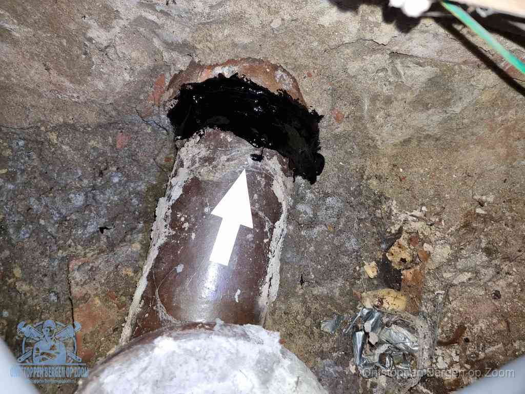 Een oude gres rioolbuis met een beschadigde koppeling onder de vloer, oorzaak van terugkerende structurele wc-problemen in Bergen op Zoom