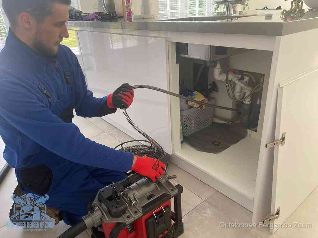 Een monteur reinigt de keukenafvoer grondig met een veermachine om terugkerende gootsteenverstoppingen te voorkomen in Bergen op Zoom