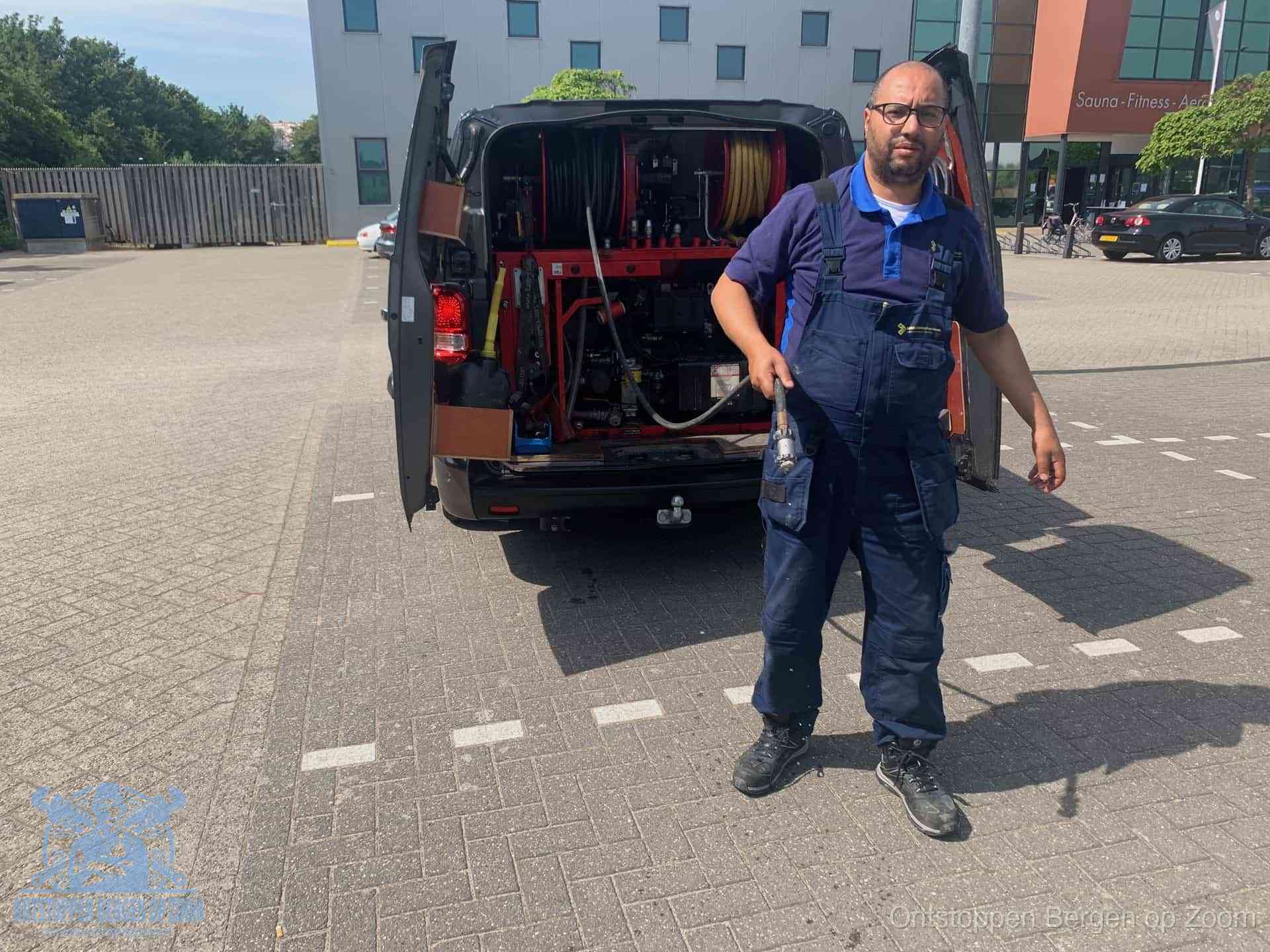 Een monteur bij zijn bestelbus met een hogedruk- en rioolreinigingsunit, klaar om de oorzaak van terugkerende wc-verstoppingen aan te pakken in Bergen op Zoom