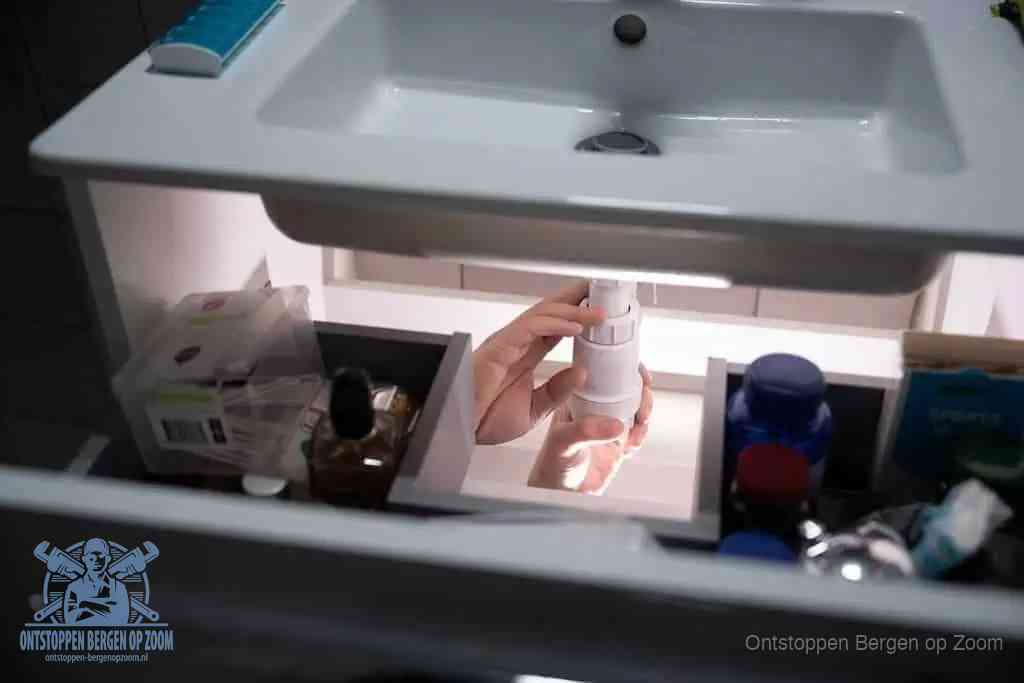Een pompfles met zeep boven een wastafel in de toiletruimte, de warm water en afwasmiddel-methode om de wc te ontstoppen in Bergen op Zoom