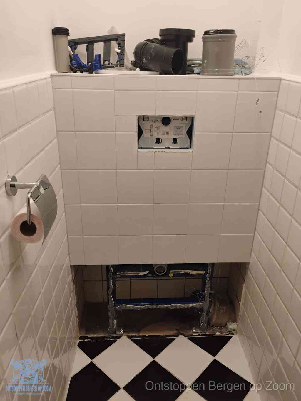 Een toiletruimte waar het hangtoilet en de inbouwreservoir-onderdelen zijn vrijgelegd voor onderhoud, periodiek nazicht voorkomt een wc-verstopping in Bergen op Zoom